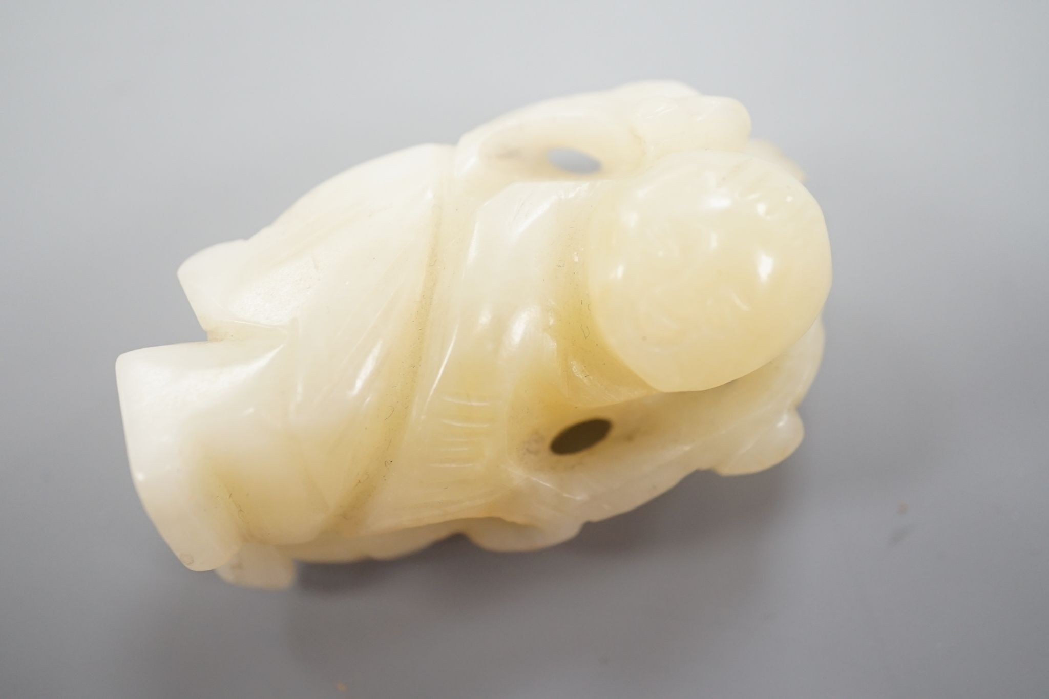 A Chinese bowenite jade carving of a boy with a branch, 5.5 cms high.